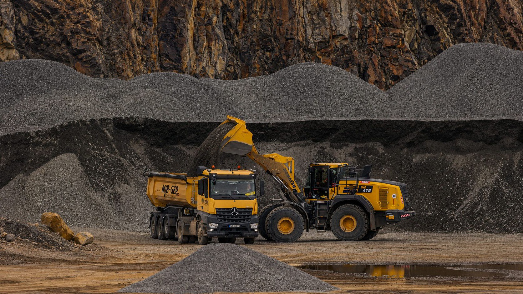 Pá carregadeira despejando minério em caminhão numa mineradora