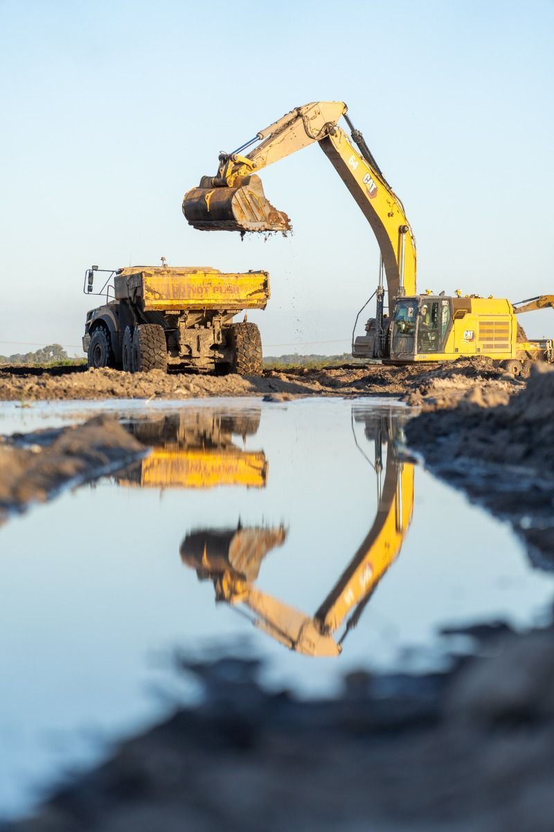 Pá carregadeira operando em pátio de mineração, cercada por pilhas de britas